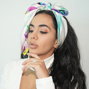 Woman wearing white floral silk headscarf tied in a chic bow 