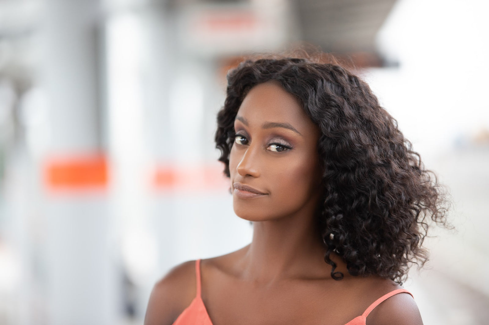 Woman wearing a natural black curly bob wig and rust coloured vest
