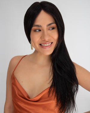 Happy woman wearing a long straight wig with middle parting and an orange dress
