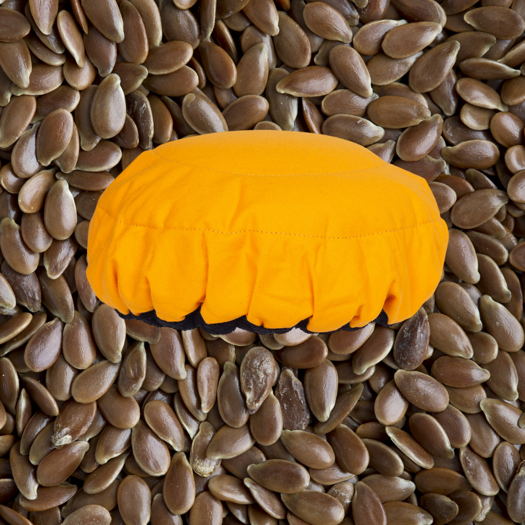Amber yellow microwavable flaxseed-filled deep conditioning heat cap with flaxseeds in the background