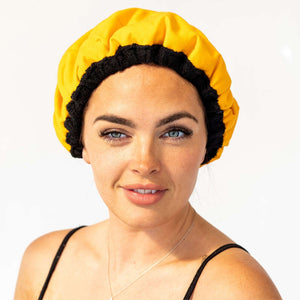Woman wearing yellow Lava Cap microwavable heat cap for hair treatments