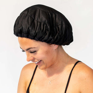 Woman wearing black Lava Cap microwavable heat cap for hair treatments