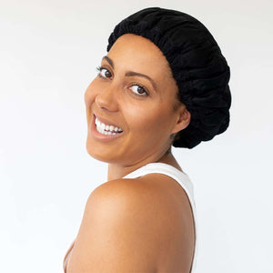 Woman wearing black Lava Cap microwavable heat cap for hair treatments