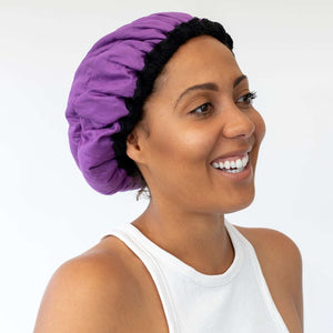 Woman wearing purple Lava Cap microwavable heat cap for hair treatments