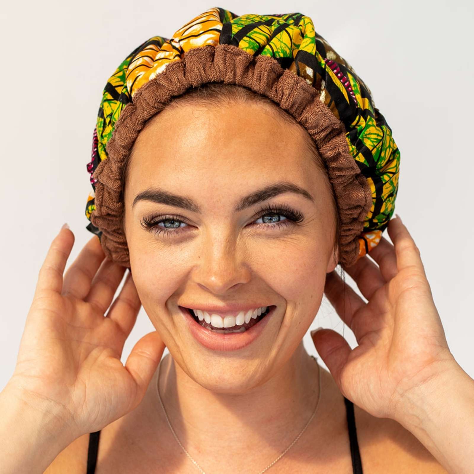 Woman wearing African print Lava Cap microwavable heat cap for hair treatments