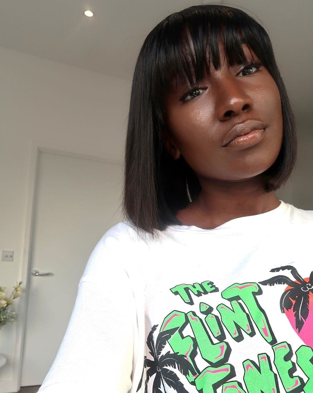 woman wearing full lace frontal bob wig with fringe and flintstones tshirt